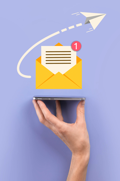 A hand holds up a smartphone. Above the phone is an email graphic