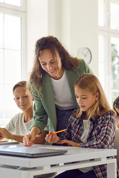 Teacher helping student at their desk in the classroom